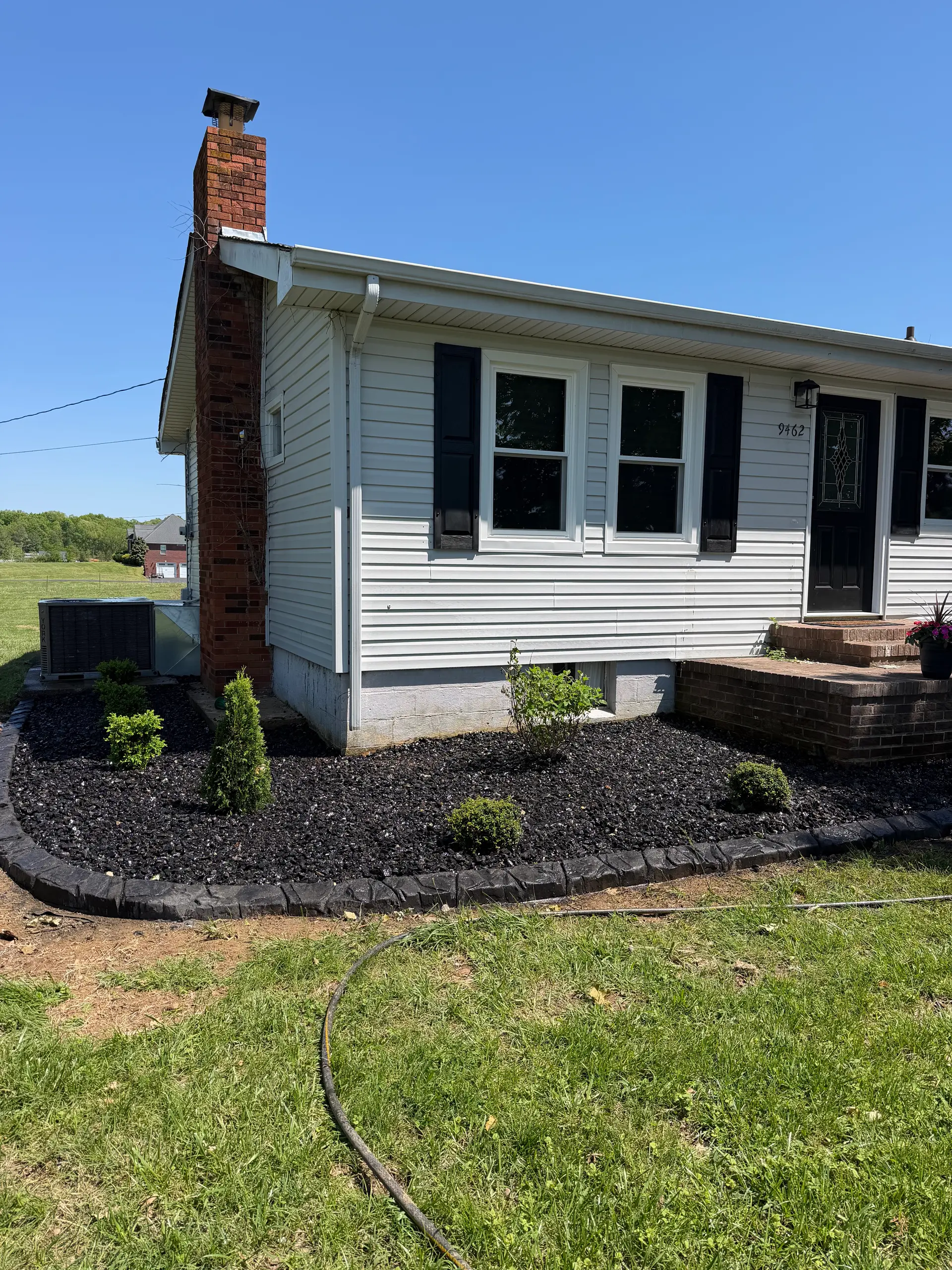 Black mulch landscape beds with stone edging along a ranch home in Paducah